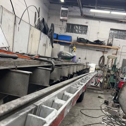 Long steel trailer frame set up for welding on the J&J Multiservices shop floor
